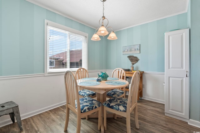 dining room featuring a textured ceiling, ornamental molding, and wood finished floors