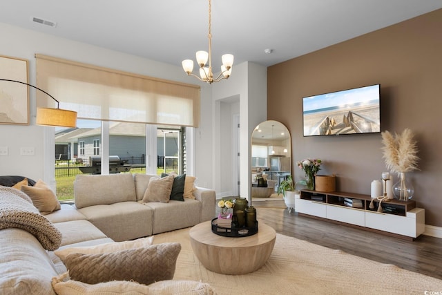 living area with a notable chandelier, visible vents, and wood finished floors