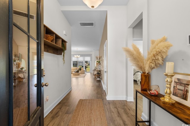 hallway with visible vents, baseboards, and wood finished floors
