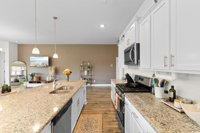 kitchen featuring appliances with stainless steel finishes, light wood-type flooring, a sink, light stone counters, and white cabinets