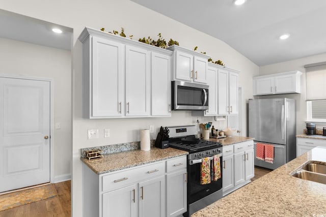 kitchen with dark wood-style flooring, appliances with stainless steel finishes, lofted ceiling, recessed lighting, and white cabinetry