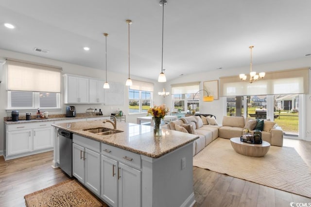 kitchen with a sink, a center island with sink, wood finished floors, and a chandelier