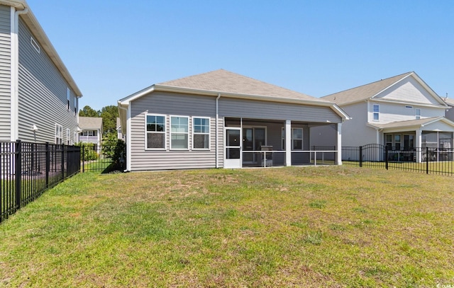 rear view of house featuring a yard, a fenced backyard, and a sunroom