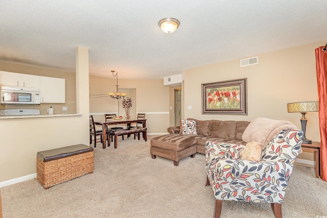 living area with baseboards, light colored carpet, a textured ceiling, and visible vents