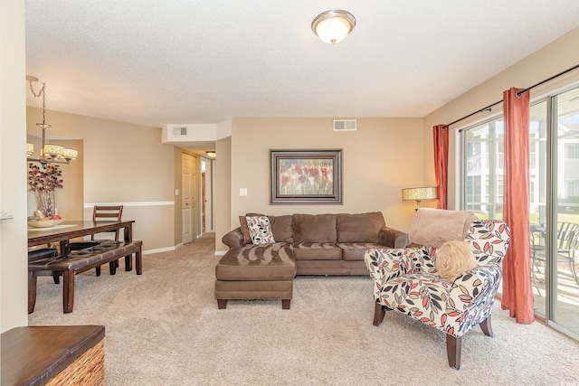 living area featuring visible vents, baseboards, an inviting chandelier, and light colored carpet