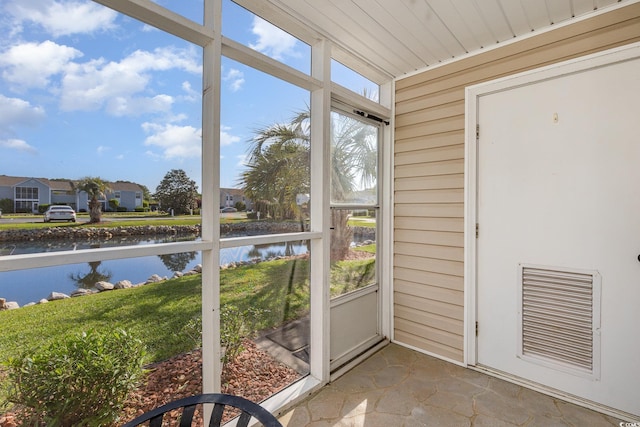 unfurnished sunroom featuring visible vents, a water view, and a residential view