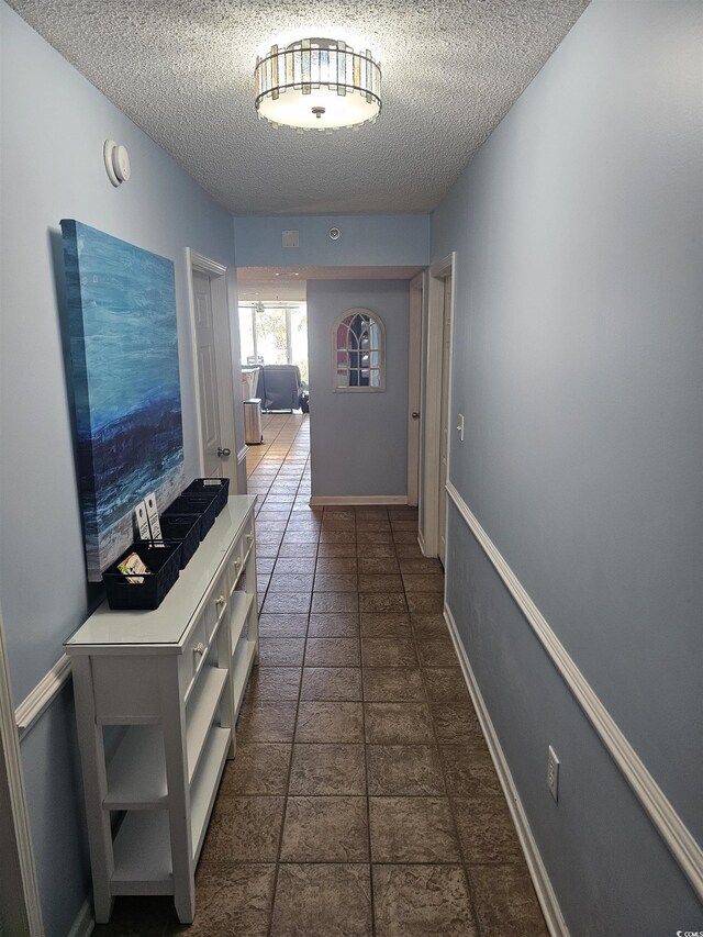hall with a textured ceiling and baseboards