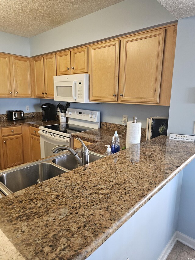 kitchen with white appliances, a textured ceiling, light tile patterned flooring, and baseboards
