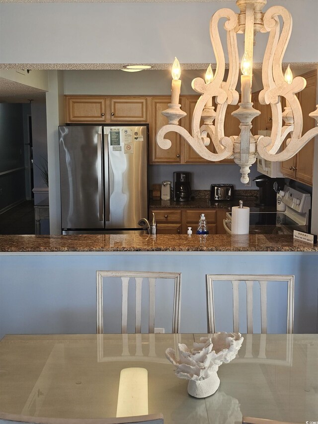 kitchen featuring freestanding refrigerator and dark stone countertops