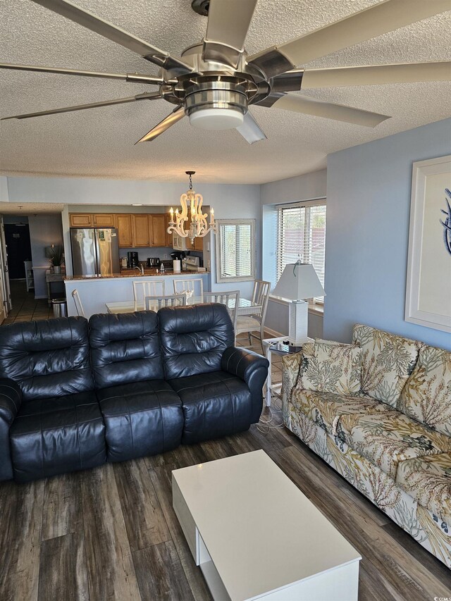 living room featuring a ceiling fan, a chandelier, dark wood-style floors, and a textured ceiling