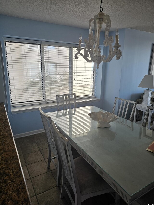 dining area with a chandelier, baseboards, a textured ceiling, and tile patterned floors