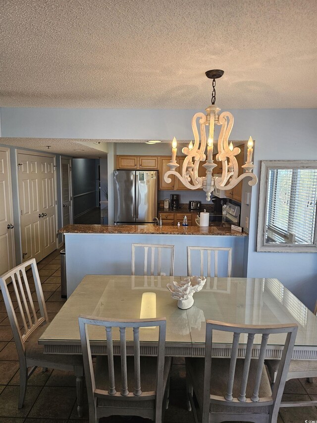 dining room featuring a chandelier, a textured ceiling, and dark tile patterned floors