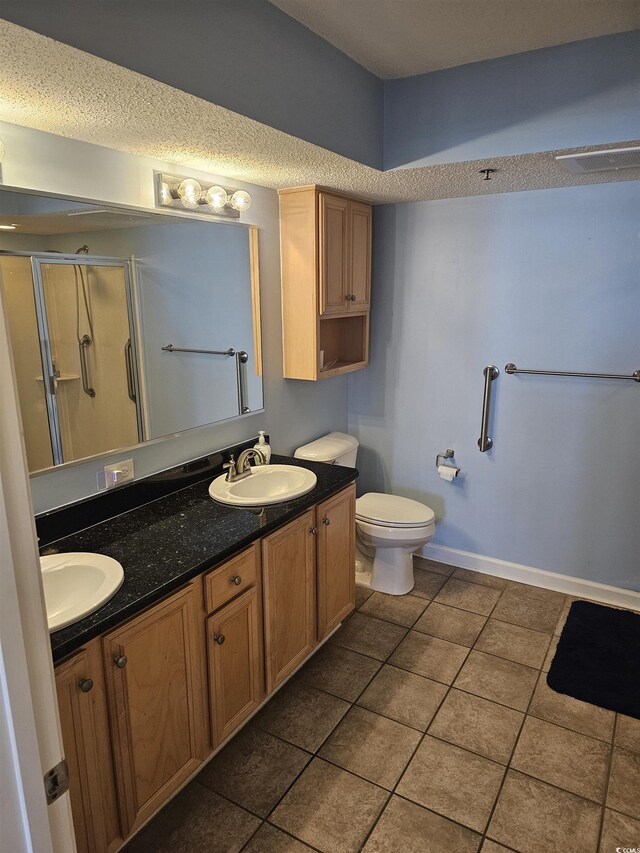 full bathroom with a shower stall, double vanity, tile patterned floors, toilet, and baseboards
