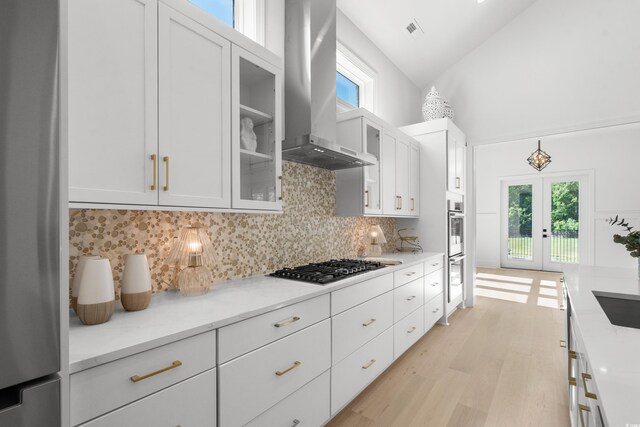 985 Shipmaster Ave, Myrtle Beach, SC 29579 - kitchen with wall chimney range hood, white cabinets, light wood-style flooring, stainless steel appliances, and backsplash