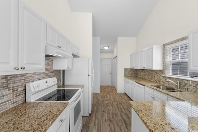 kitchen featuring white appliances, white cabinets, under cabinet range hood, and a sink