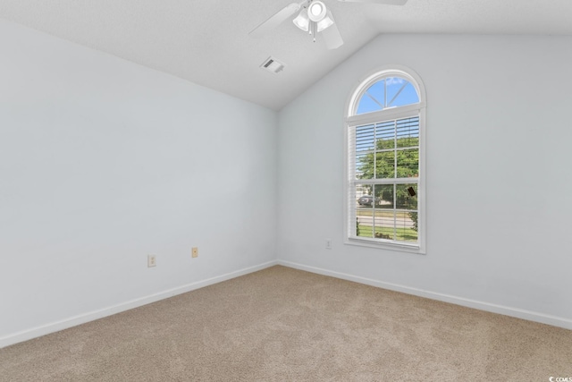 carpeted spare room with ceiling fan, visible vents, baseboards, and vaulted ceiling