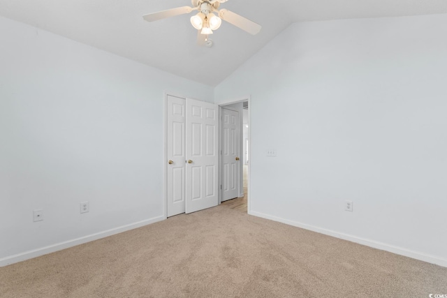 unfurnished bedroom with light colored carpet, a ceiling fan, baseboards, vaulted ceiling, and a closet