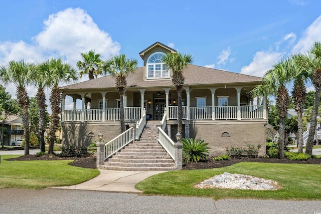 beach home with covered porch, stucco siding, a front yard, and stairs