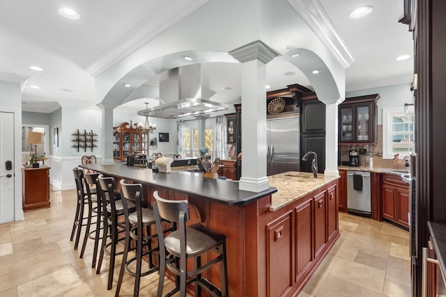 kitchen featuring island exhaust hood, ornate columns, stainless steel appliances, a spacious island, and ornamental molding