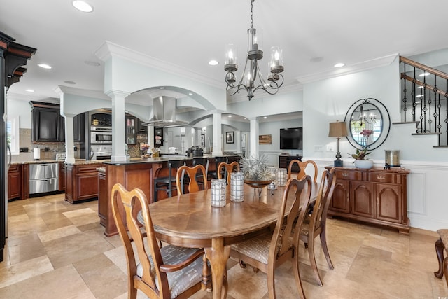 dining room with an inviting chandelier, ornamental molding, and decorative columns