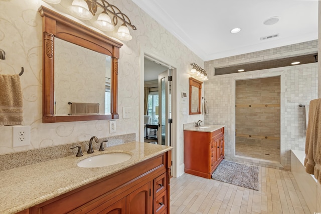full bathroom with two vanities, a tile shower, visible vents, and a sink