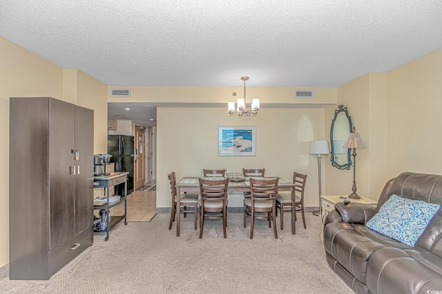 dining room featuring visible vents, a textured ceiling, a chandelier, and light carpet