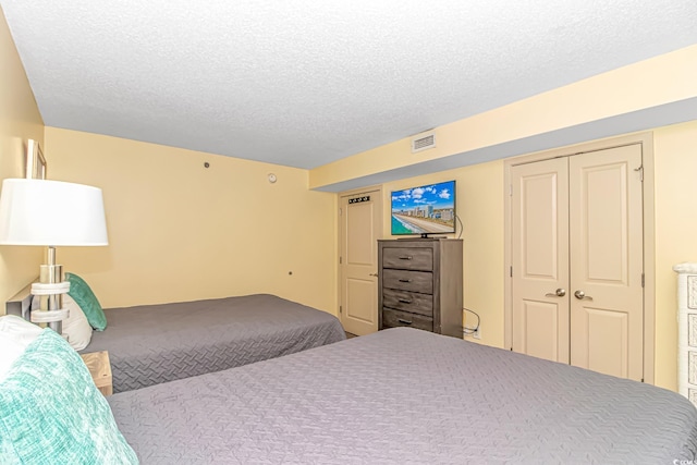 bedroom featuring carpet flooring, a textured ceiling, visible vents, and a closet