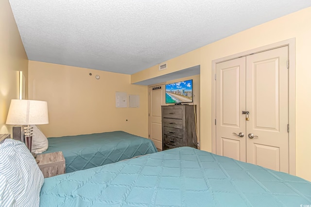 bedroom with a closet, a textured ceiling, and visible vents