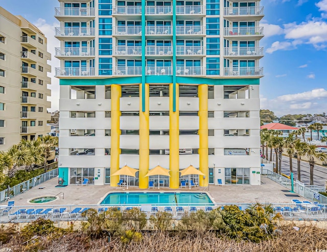 view of building exterior with a community pool and fence