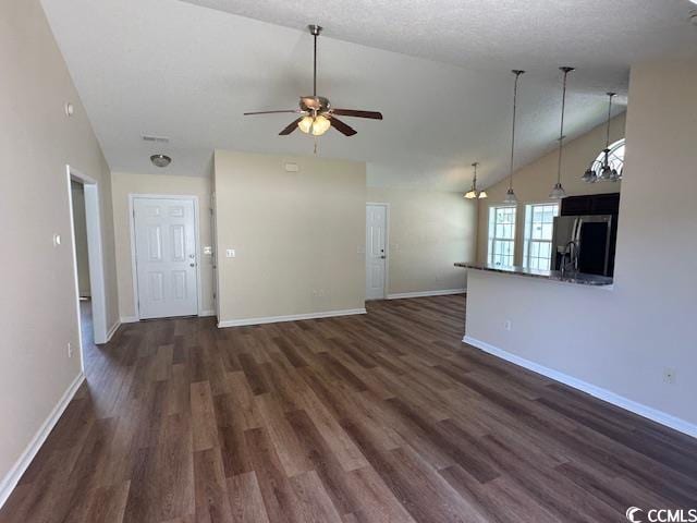 unfurnished living room with dark wood-type flooring, baseboards, ceiling fan, and vaulted ceiling