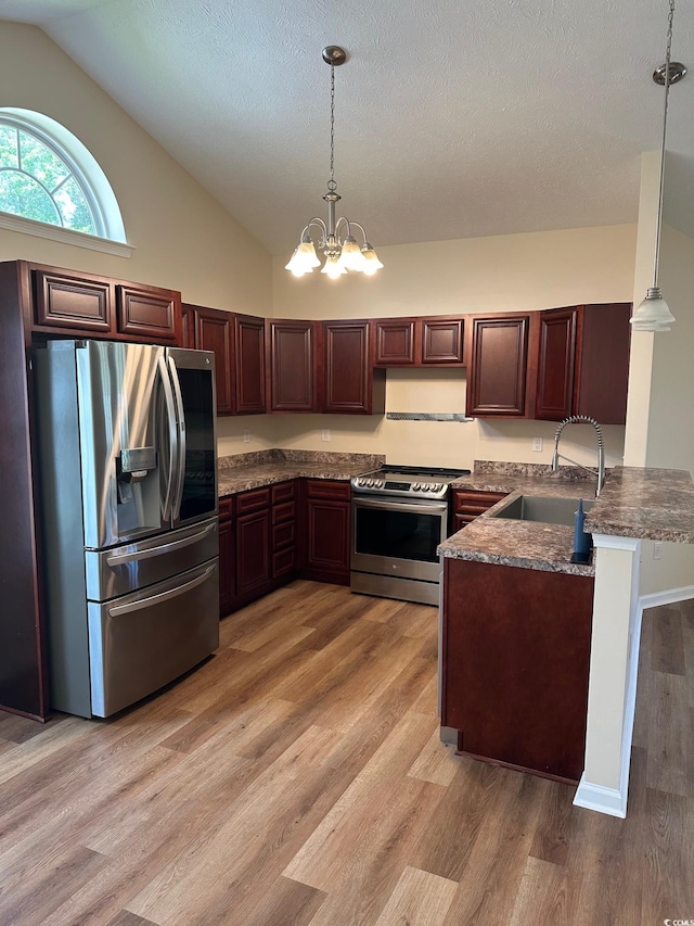 kitchen featuring a sink, light wood-style floors, stainless steel appliances, a peninsula, and vaulted ceiling