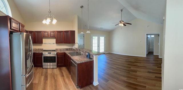 kitchen with appliances with stainless steel finishes, a sink, a peninsula, open floor plan, and wood finished floors