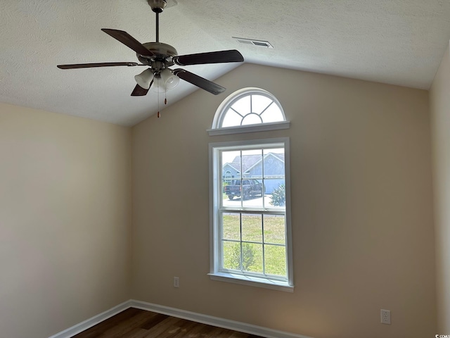 unfurnished room with visible vents, dark wood-style flooring, a textured ceiling, a ceiling fan, and vaulted ceiling