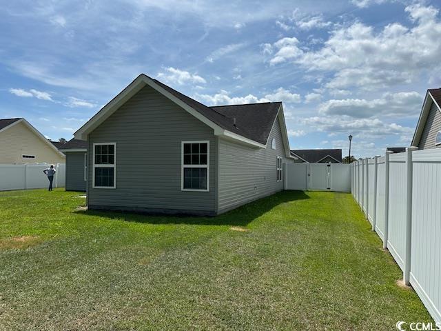 rear view of property featuring a fenced backyard, a yard, and a gate