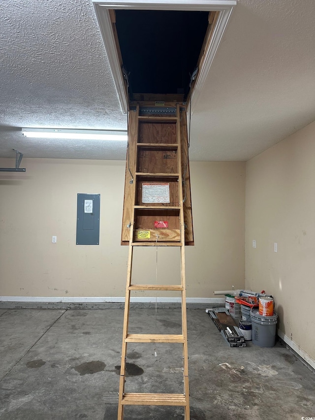 interior space featuring concrete flooring, baseboards, a textured ceiling, and electric panel