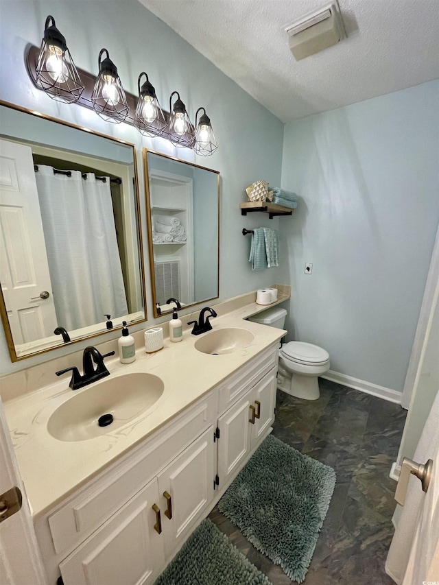 full bathroom with a sink, double vanity, toilet, and a textured ceiling