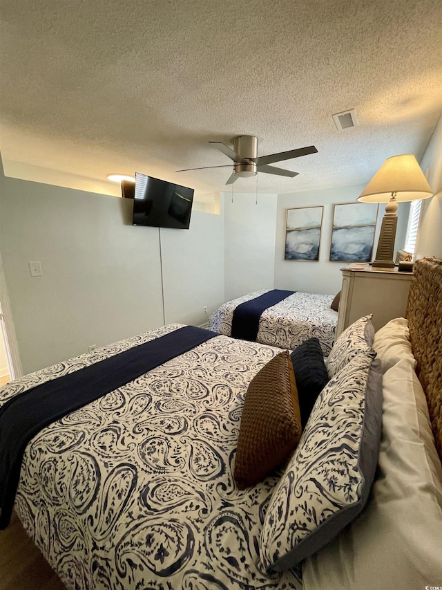 bedroom featuring a ceiling fan, a textured ceiling, and visible vents