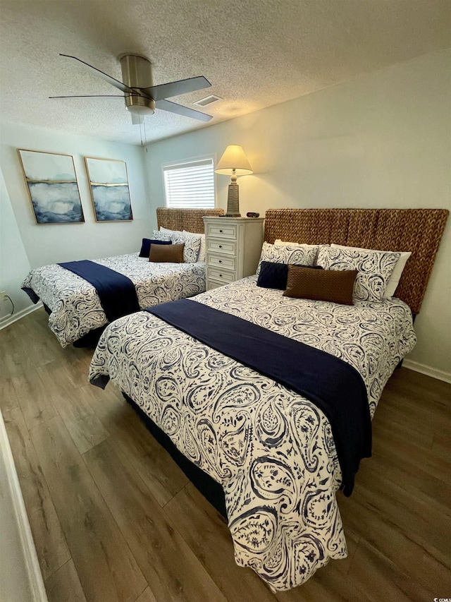 bedroom featuring a textured ceiling, ceiling fan, wood finished floors, and visible vents