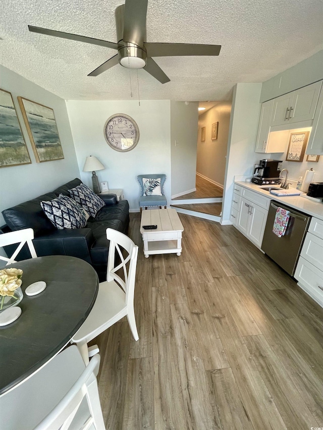 living area with light wood-style floors, baseboards, ceiling fan, and a textured ceiling