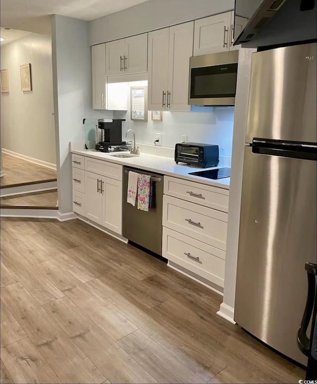 kitchen with light wood-style floors, light countertops, white cabinets, and stainless steel appliances