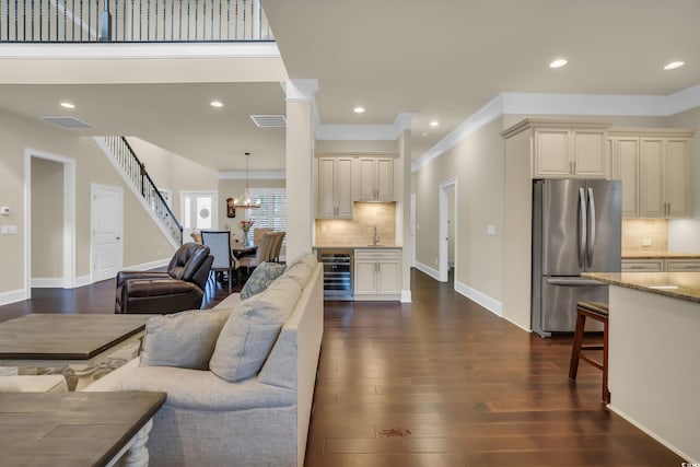 living area featuring beverage cooler, ornamental molding, visible vents, dark wood-style floors, and stairway