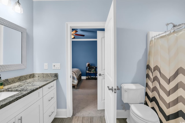 ensuite bathroom with vanity, wood finished floors, toilet, baseboards, and ensuite bath