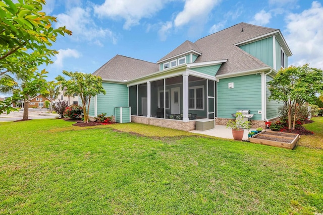 rear view of house featuring a yard, a patio, a shingled roof, and a sunroom