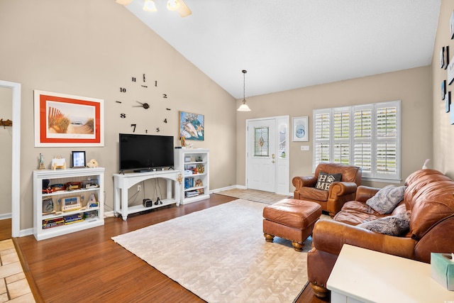 living room with baseboards, wood finished floors, and high vaulted ceiling