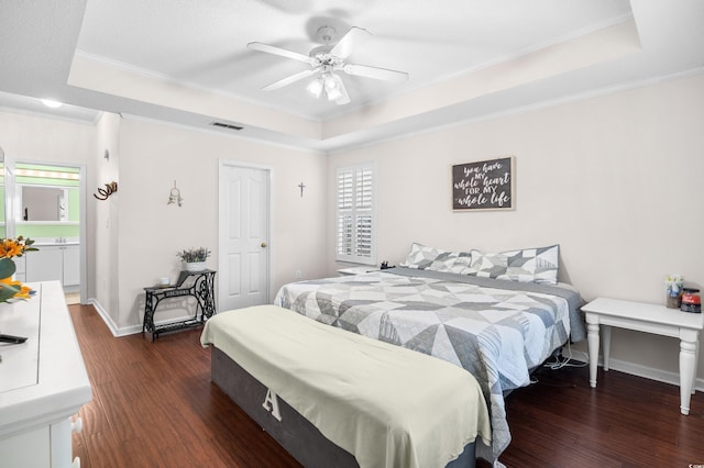 bedroom featuring visible vents, wood finished floors, a raised ceiling, baseboards, and ornamental molding