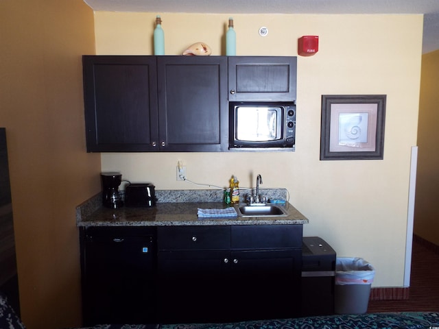 kitchen with a sink, black microwave, and dark countertops