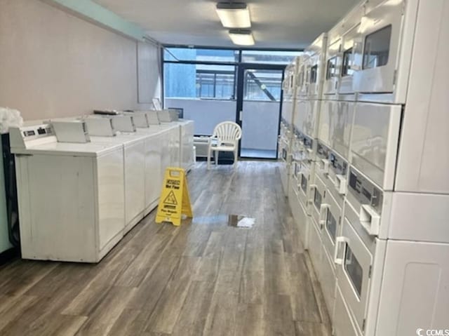 shared laundry area with washing machine and dryer, stacked washer / dryer, and wood finished floors
