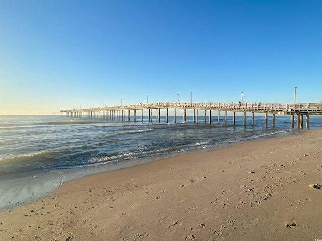 view of dock with a beach view, a water view, and a pier