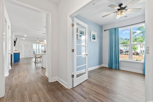 entryway with baseboards, ceiling fan with notable chandelier, wood finished floors, and visible vents