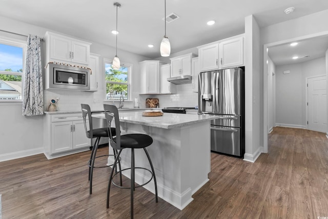 kitchen with under cabinet range hood, dark wood-style flooring, appliances with stainless steel finishes, and white cabinetry